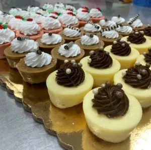 Tray of mini cheesecakes topped with whipped cream and chocolate swirls