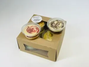 Open gift box of individual cheesecake cups with marble and berry swirls