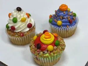 Three candy-topped cupcakes with red, blue and white frosting