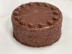 Round chocolate layer cake decorated with chocolate rosettes