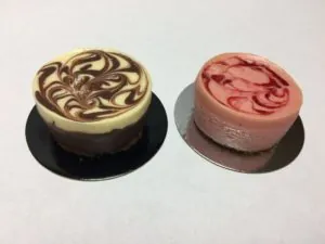 Two mini cheesecakes with chocolate and strawberry marble swirls