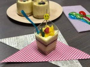 Layered cheesecake dessert cup topped with fresh fruit