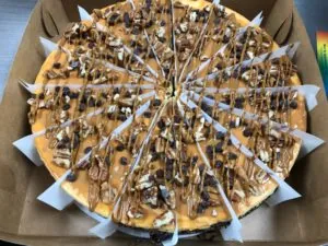 Sliced cheesecake topped with chocolate drizzle and nuts